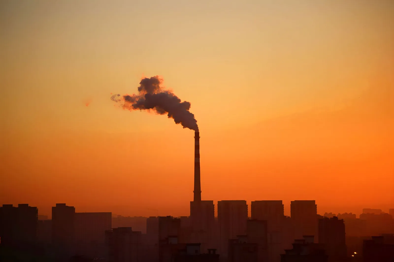 Chimenea industrial emitiendo humo al atardecer